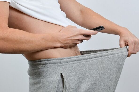 një burrë shikon pantallonat e tij në një penis të zmadhuar